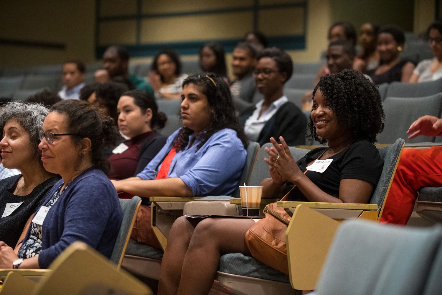 Graduate students of color seated in an auditorium at Brown University, listening and engaging during an orientation or community event.