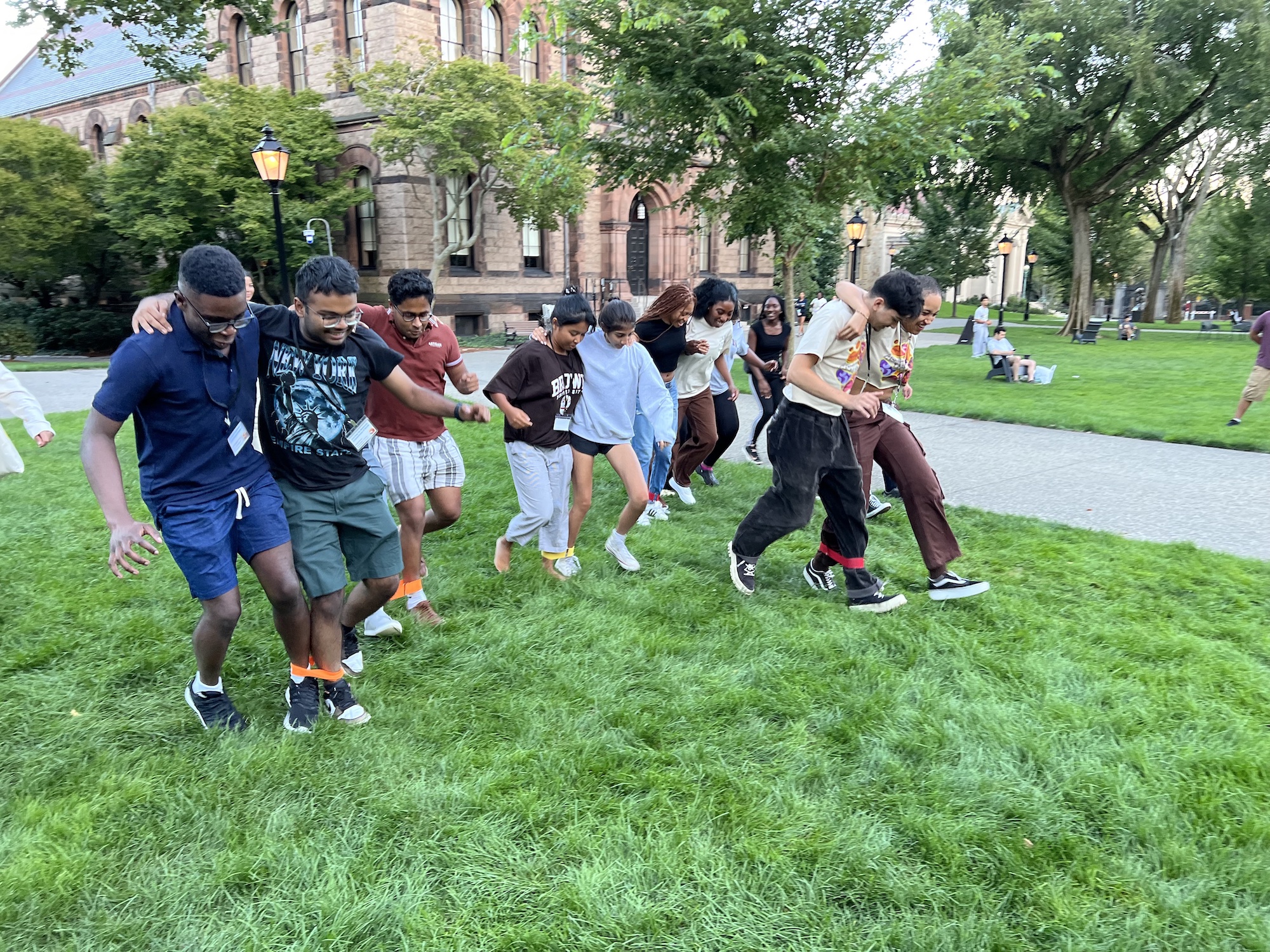 Students participating in a three-legged race on the lawn at Brown University during the Third World Transition Program, laughing and working together in teams.